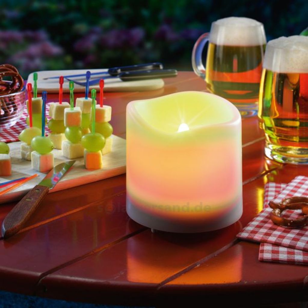 An outdoor table setting with a candle, beer, and appetizers.