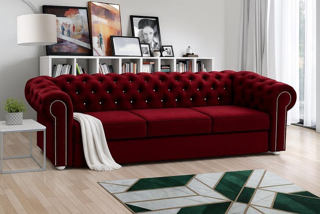 A red sofa in a living room setting with a bookshelf in the background and a rug in the foreground.