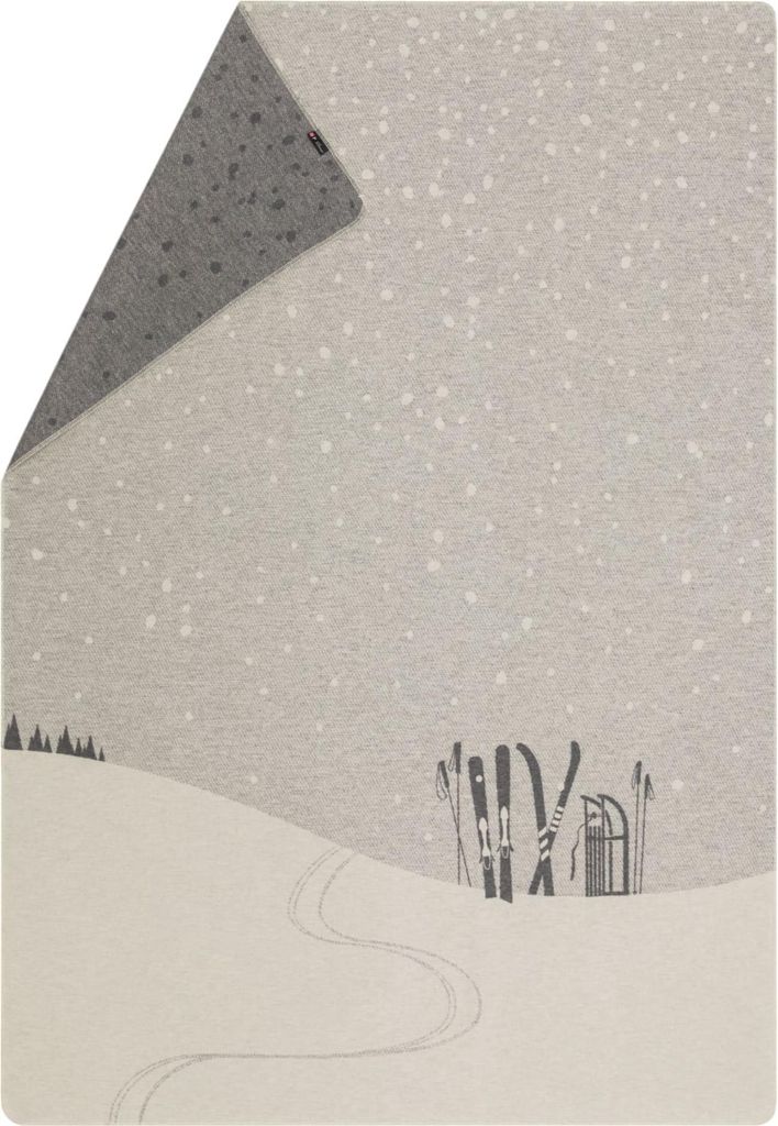 A winter scene with snow-covered hills, ski tracks, and skis leaning against a sled.