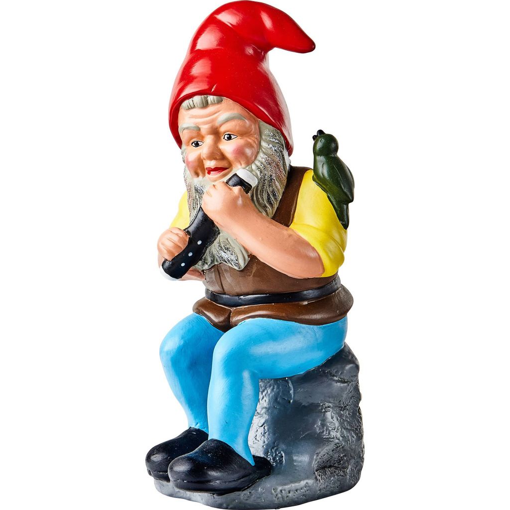 A garden gnome figurine sitting on a rock and playing a harmonica, with a small bird on its shoulder.