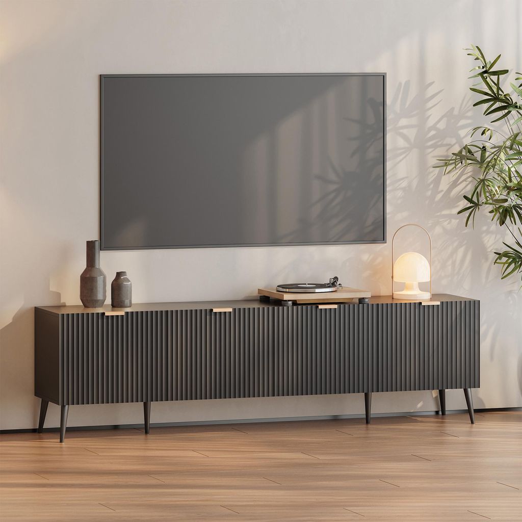 A modern media console with a television mounted above it, set in a well-lit room with a plant.