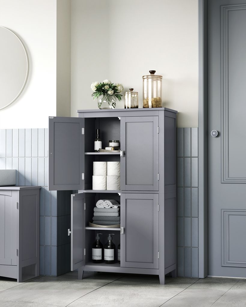 A gray bathroom cabinet with its doors open, displaying various items inside, set against a tiled wall.