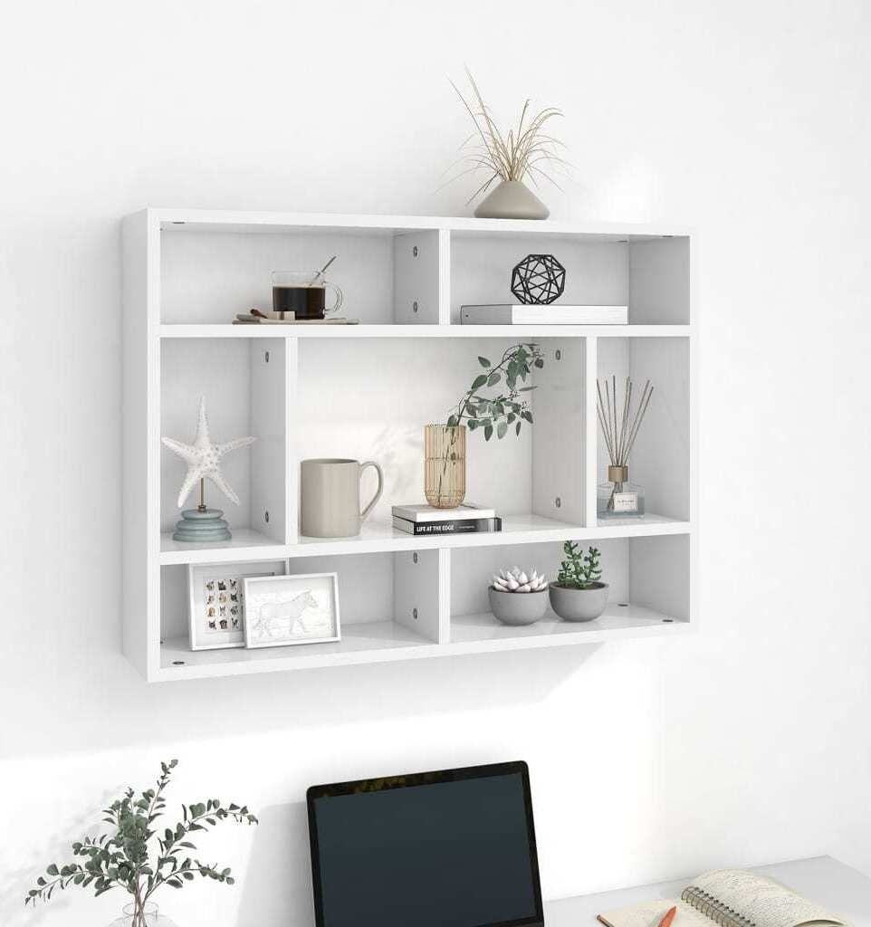 A white wall-mounted shelving unit with various decorative items on its shelves.