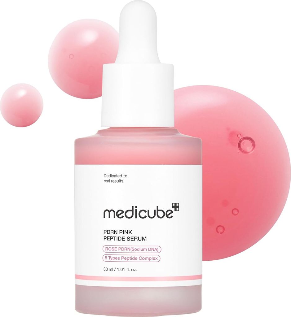 A bottle of Medicube PDRN Pink Peptide Serum with pink liquid droplets around it.