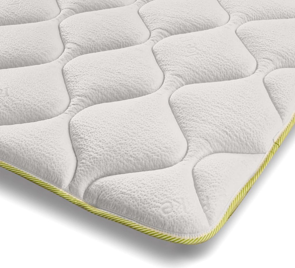 A close-up, angled view of a white mattress topper with a quilted pattern and a yellow trim.