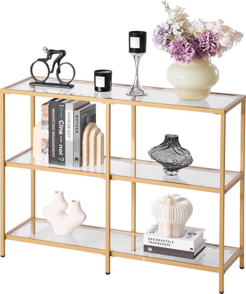 A three-tiered console table with glass shelves and a gold frame, decorated with various items.
