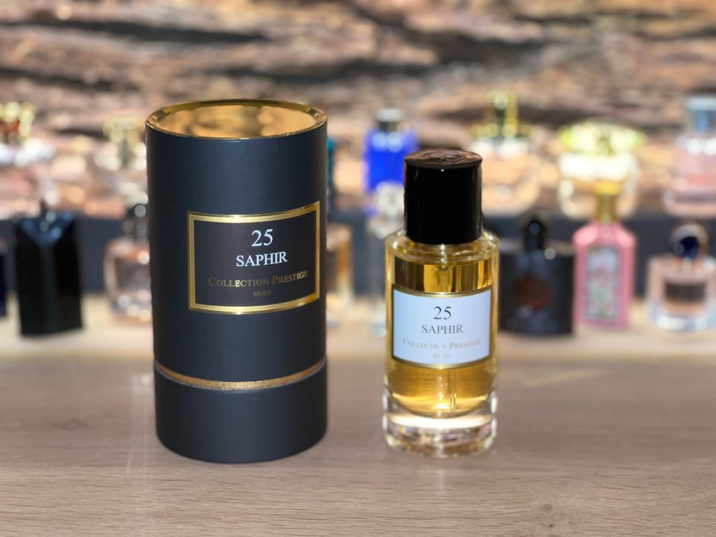 A perfume bottle and its cylindrical packaging are displayed on a shelf with other perfume bottles in the background.
