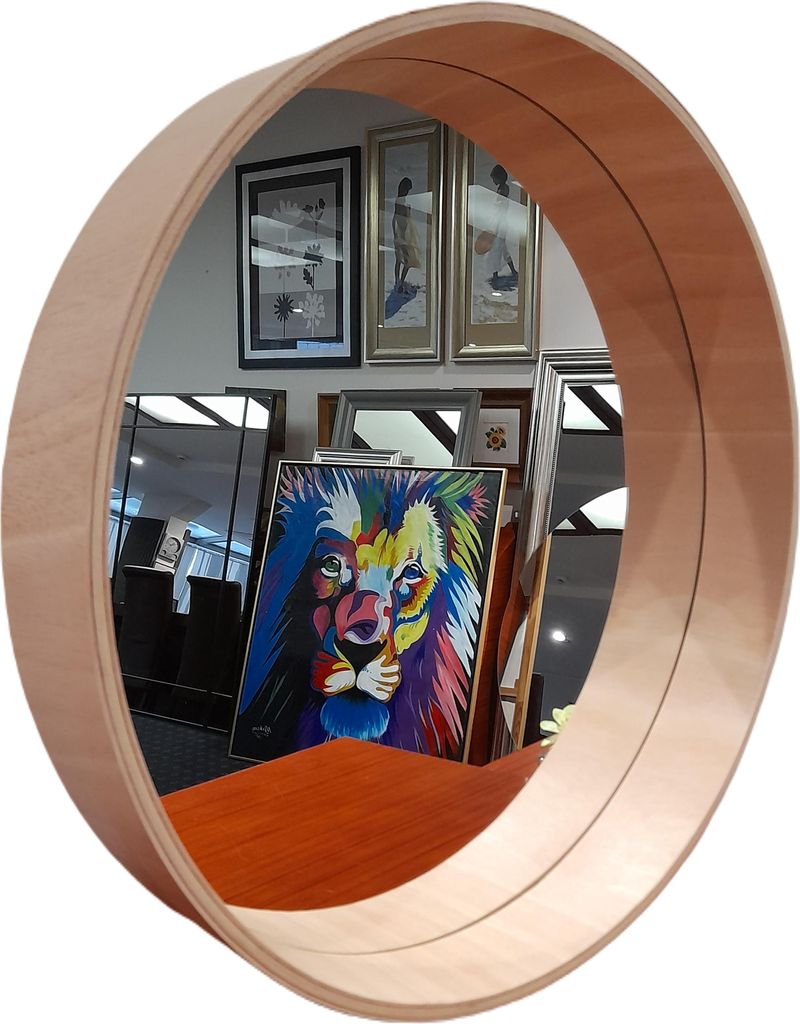 A round mirror with a wooden frame reflecting a room with artwork, including a colorful lion painting.