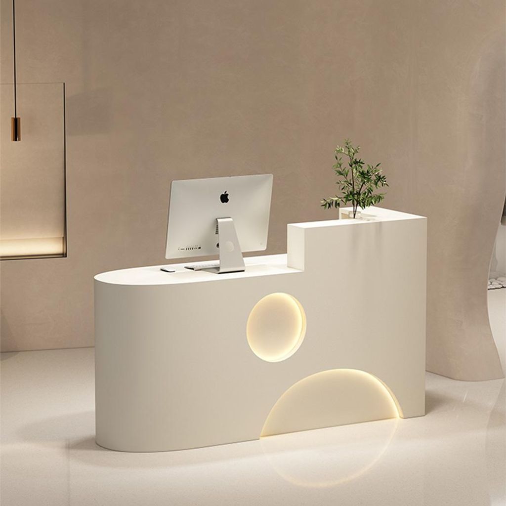 A modern reception desk with a computer and a small plant.