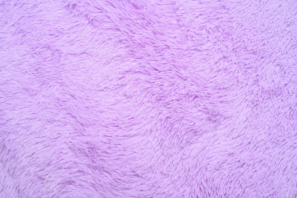A close-up, top-down view of a fluffy, violet-colored rug.