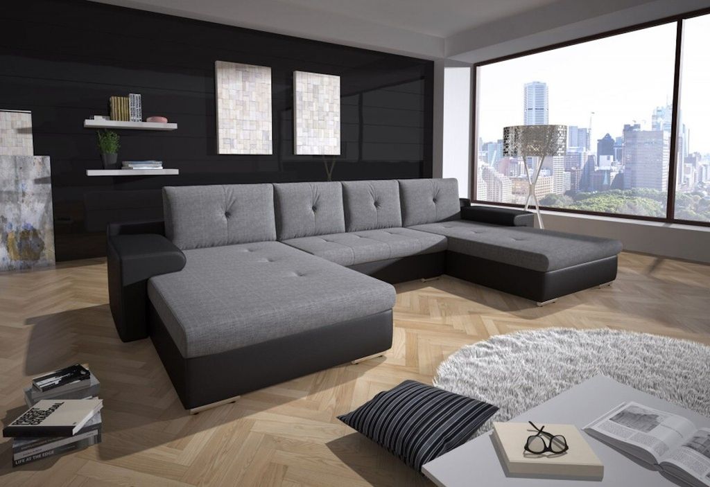 A modern living room with a large sectional sofa, a large window overlooking a city skyline, and decorative elements.