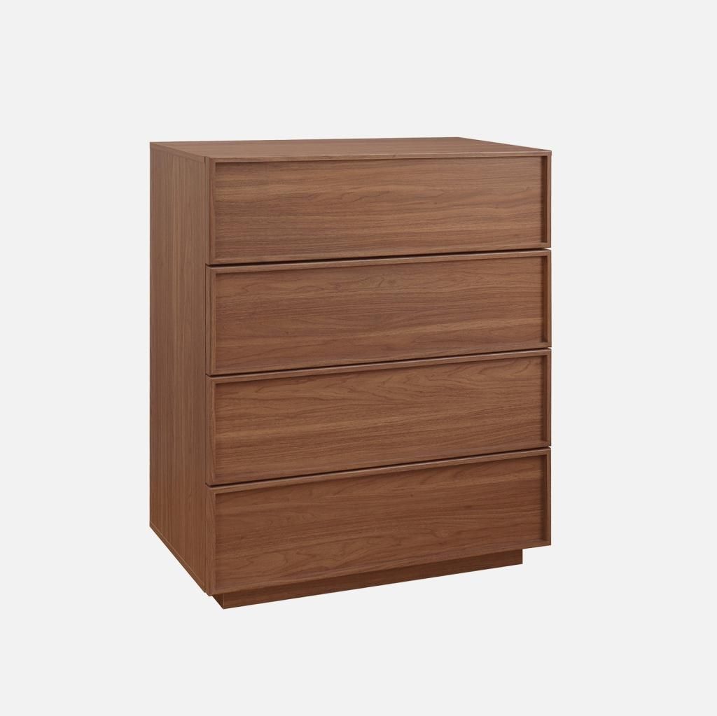 A wooden chest of drawers with four drawers against a plain background.
