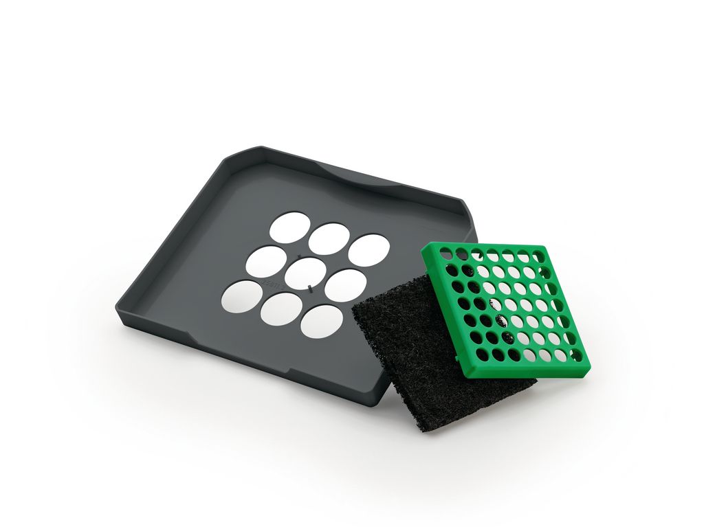 A gray tray with circular cutouts, a black filter, and a green grate are arranged on a white background.