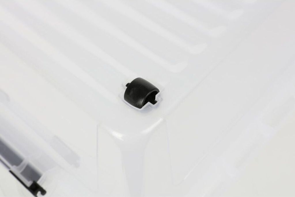 A close-up view of a black plastic clip attached to the corner of a transparent storage box.