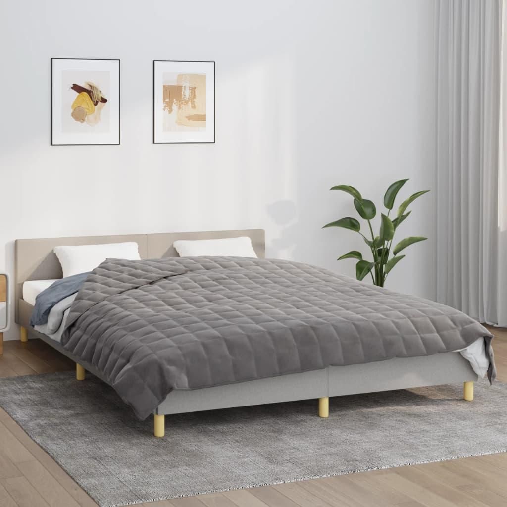 A bed with a gray weighted blanket is shown in a bedroom setting.