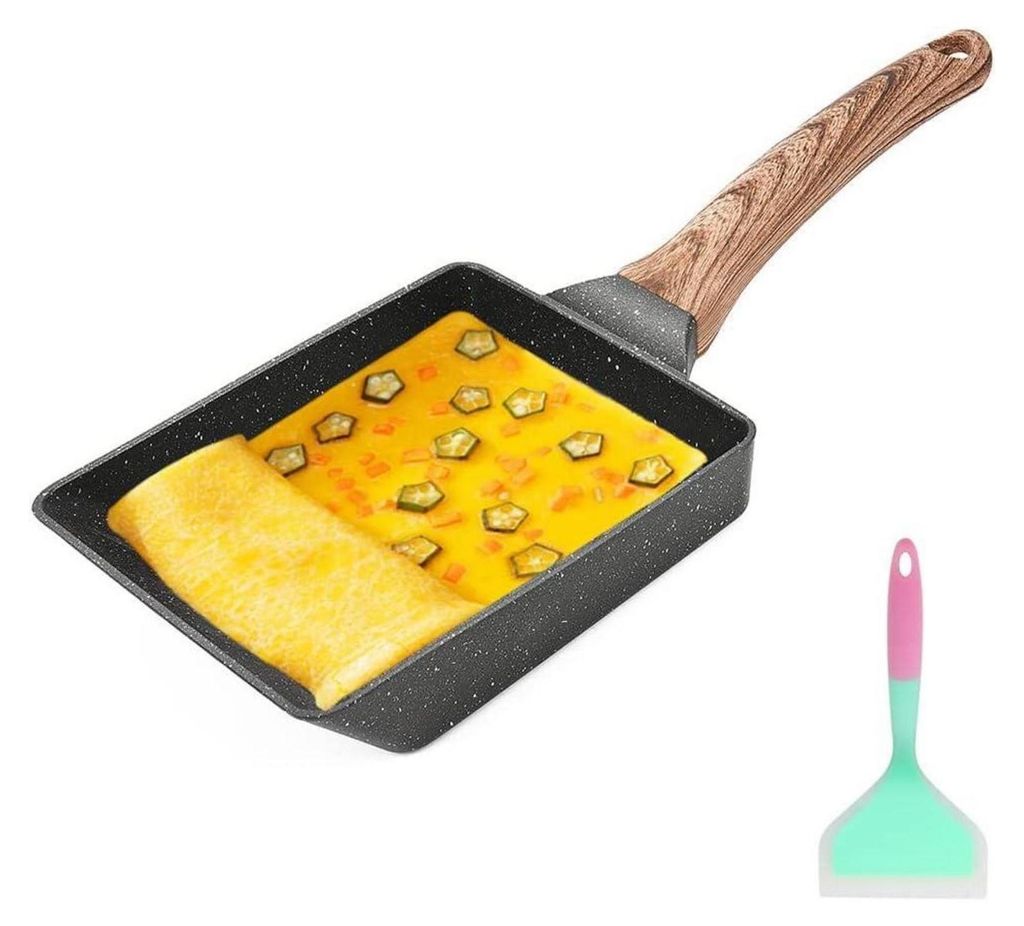 A rectangular non-stick egg pan with a wooden handle, containing a partially cooked omelet with vegetables, and a spatula next to it.