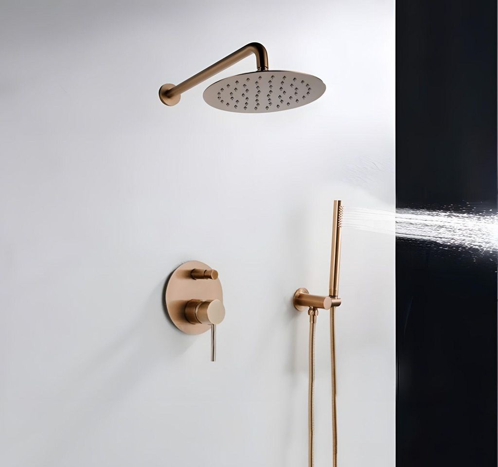 A rose gold shower set mounted on a white wall, with water spraying from the handheld showerhead.