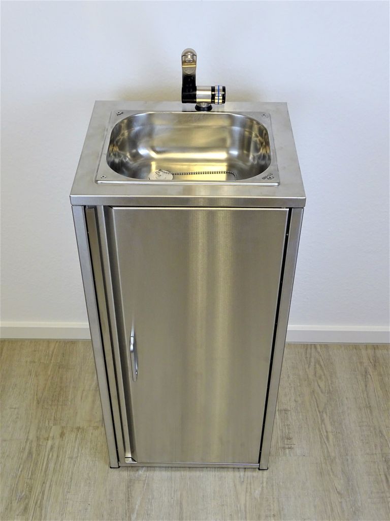 A stainless steel sink with a cabinet underneath, set against a plain wall and wooden floor.