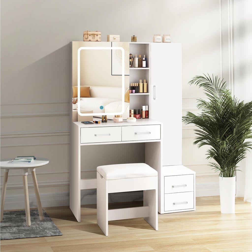 A white vanity set with a lighted mirror, drawers, and a stool, placed in a room with a plant and a small table.