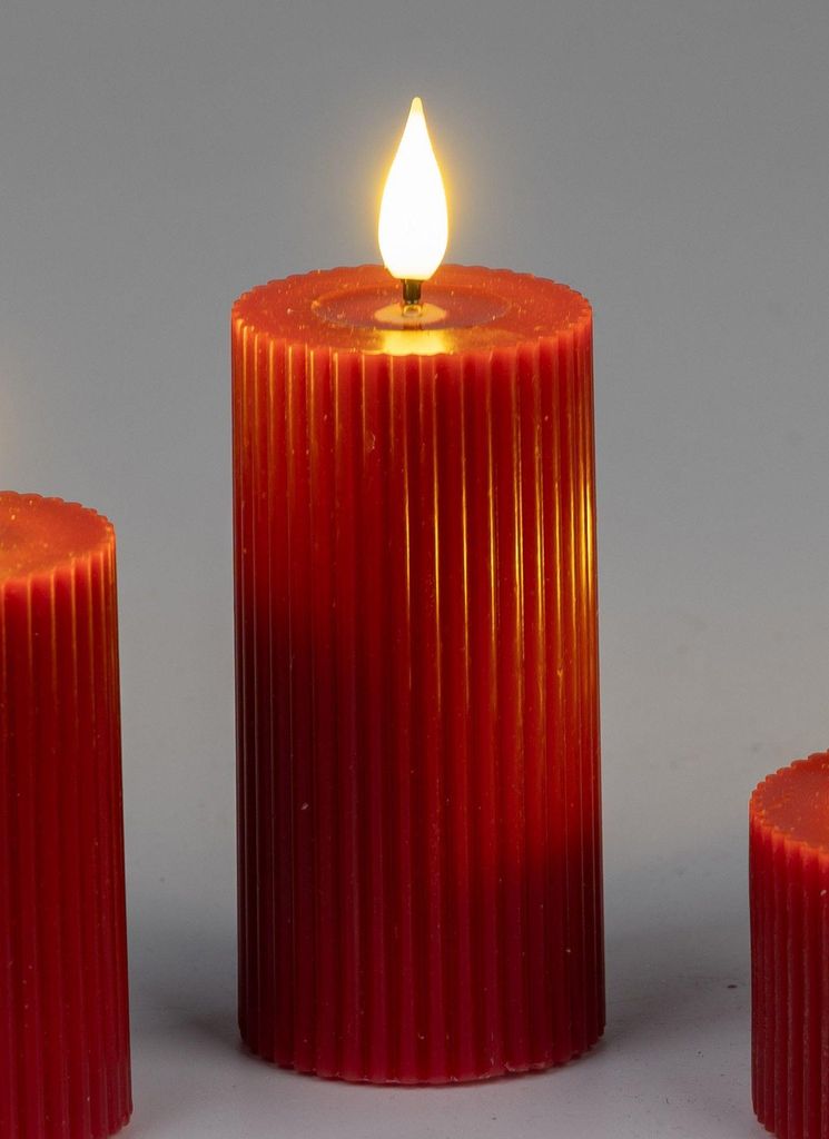 Three red LED candles with a ribbed texture and a flickering flame on a plain gray background.