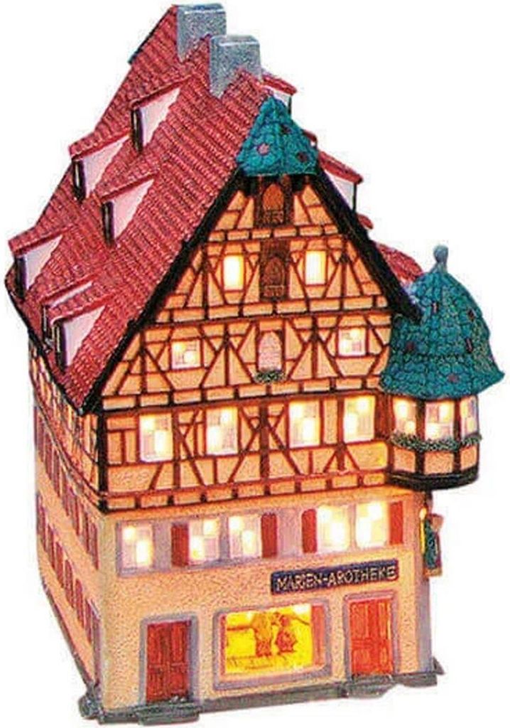 A lit-up, decorative model of a historic building, likely a pharmacy, with a red tiled roof and timber-framed upper stories.