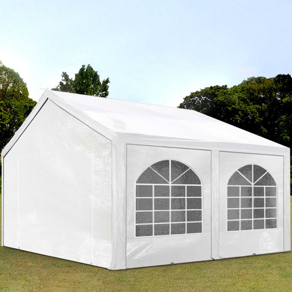A white party tent set up on a grassy lawn with trees in the background.