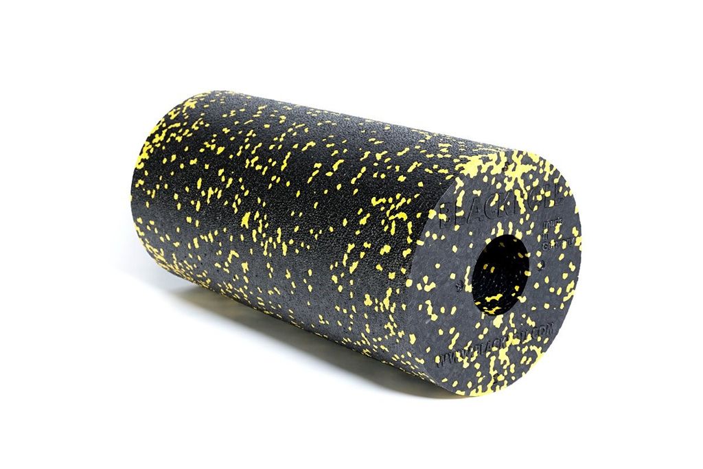 A black foam roller with yellow speckles is shown against a white background.