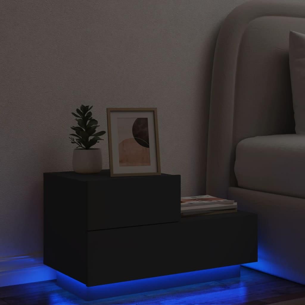 A black nightstand with LED lighting is placed next to a bed in a dimly lit room.
