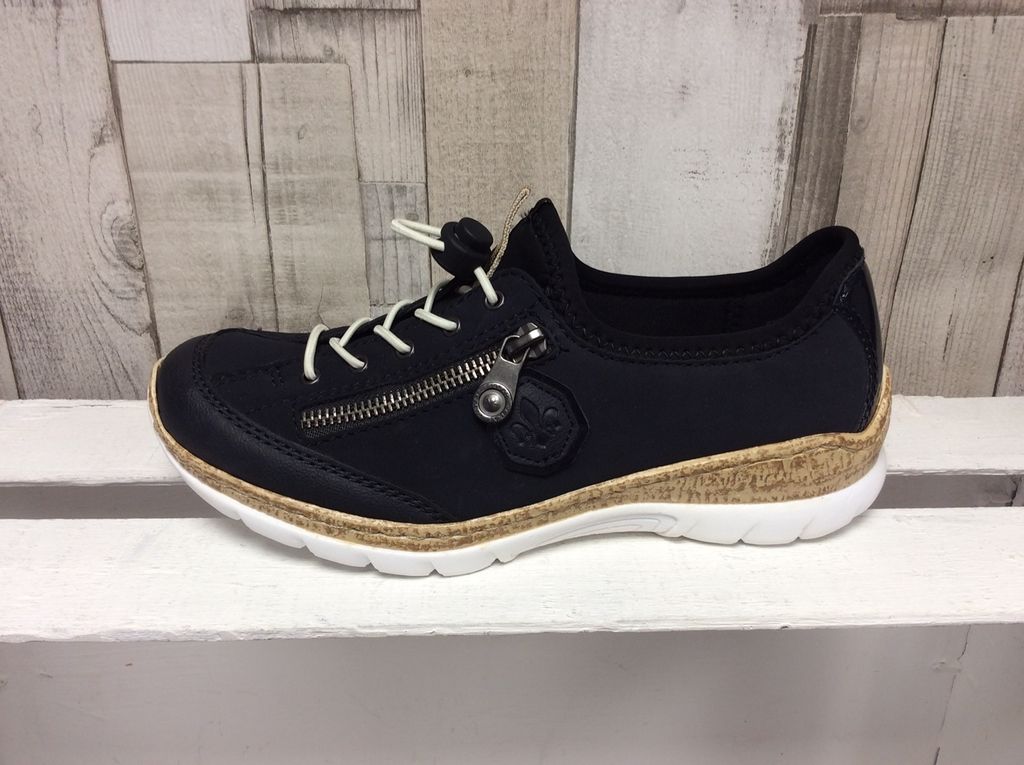 A single navy Rieker slipper is displayed on a white shelf against a light wood-paneled background.