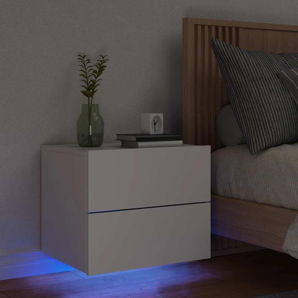 A bedside table with a plant and books next to a bed.