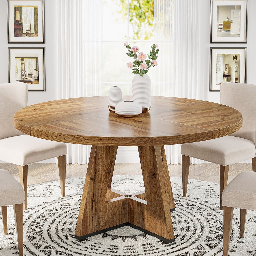 A round wooden dining table with chairs around it in a well-lit room.