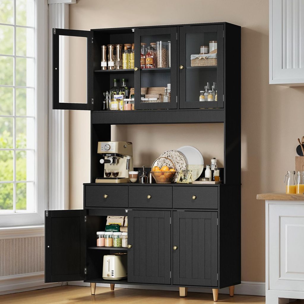 A black sideboard with glass doors and drawers, filled with kitchen items and appliances, set in a room with a window.