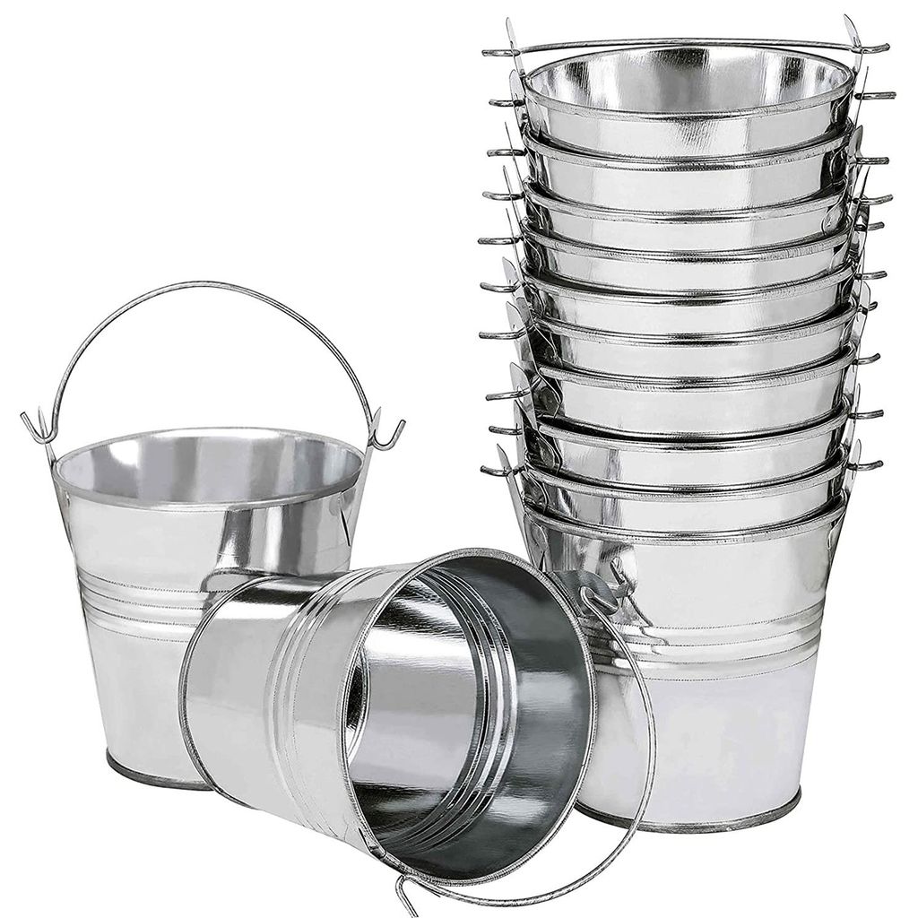 A collection of small, silver metal buckets with handles, some stacked and one lying on its side.