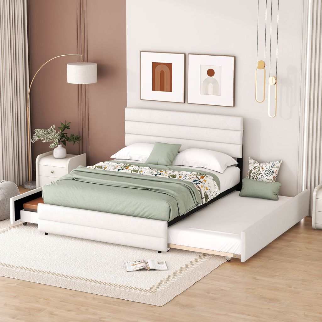 A white upholstered bed with a trundle pulled out, set in a bedroom with modern decor.