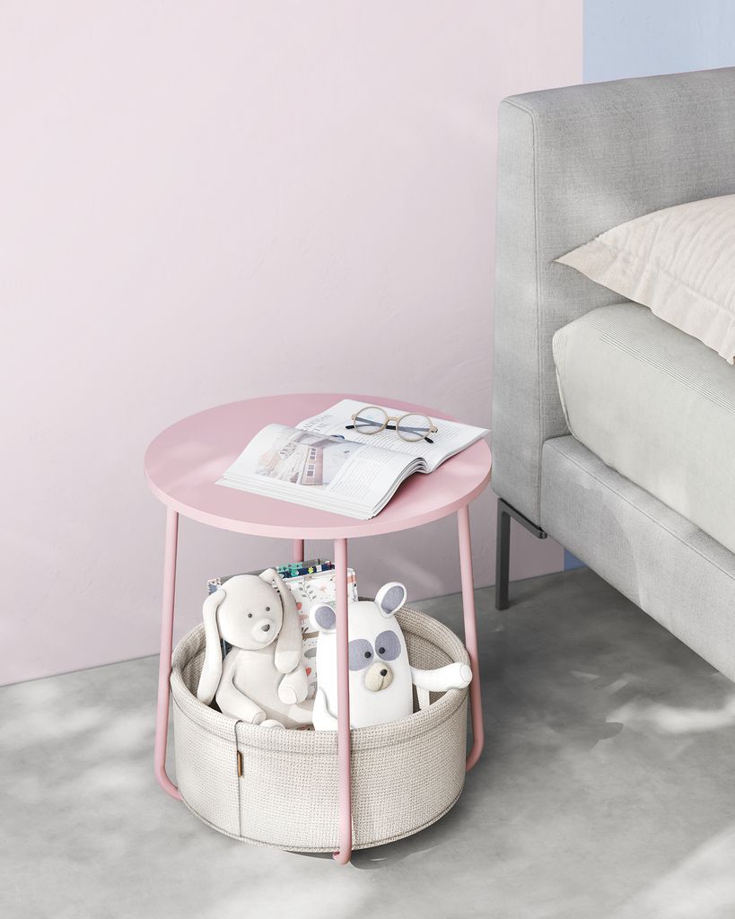 A pink side table with toys and a book next to a bed.