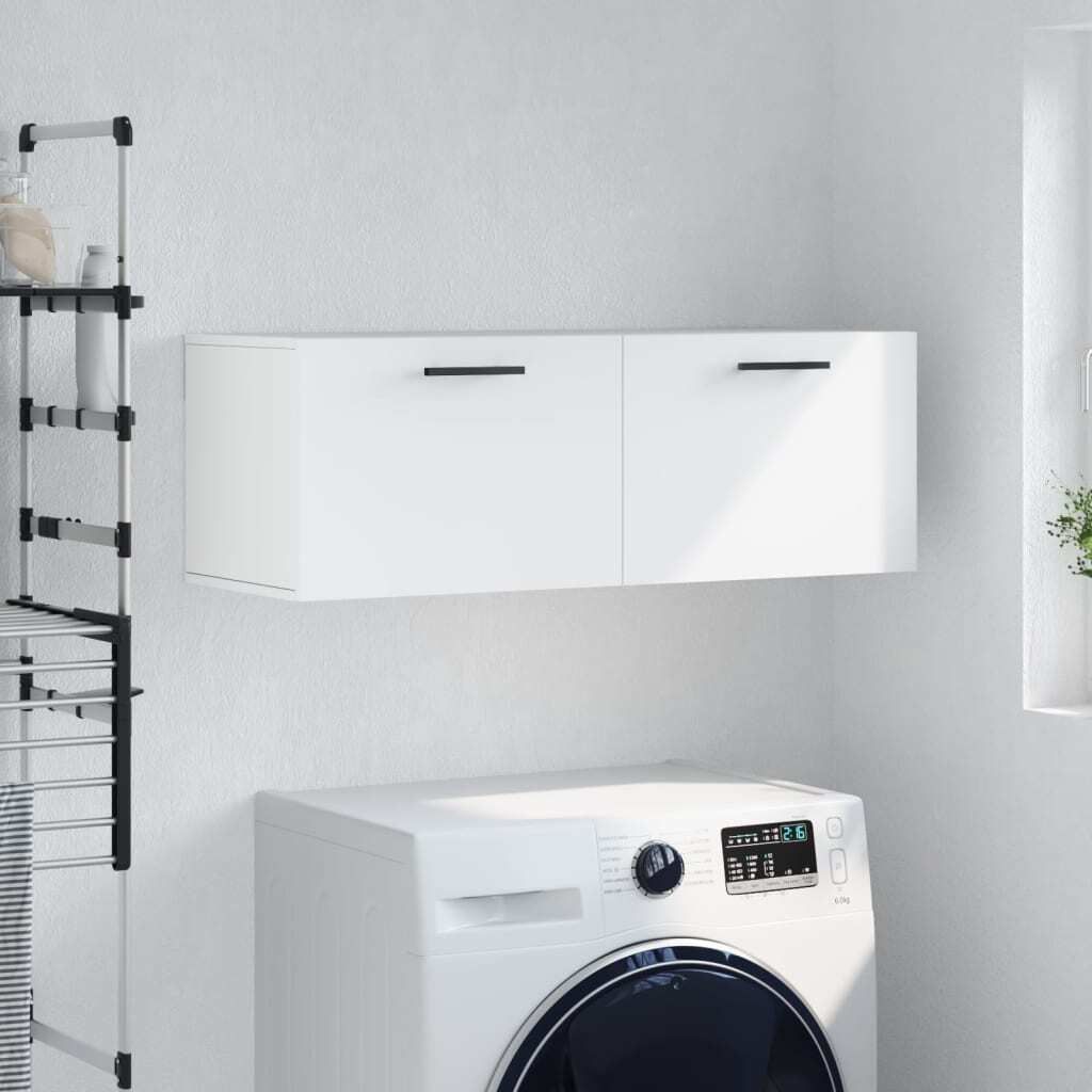 A white wall-mounted cabinet with two doors is shown above a white washing machine in a laundry room setting.