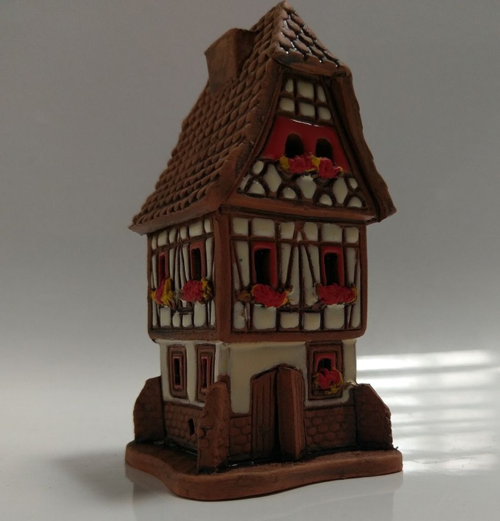 Ein Keramikmodell eines Fachwerkhauses. Das Haus ist zweistöckig mit einem steilen Dach.