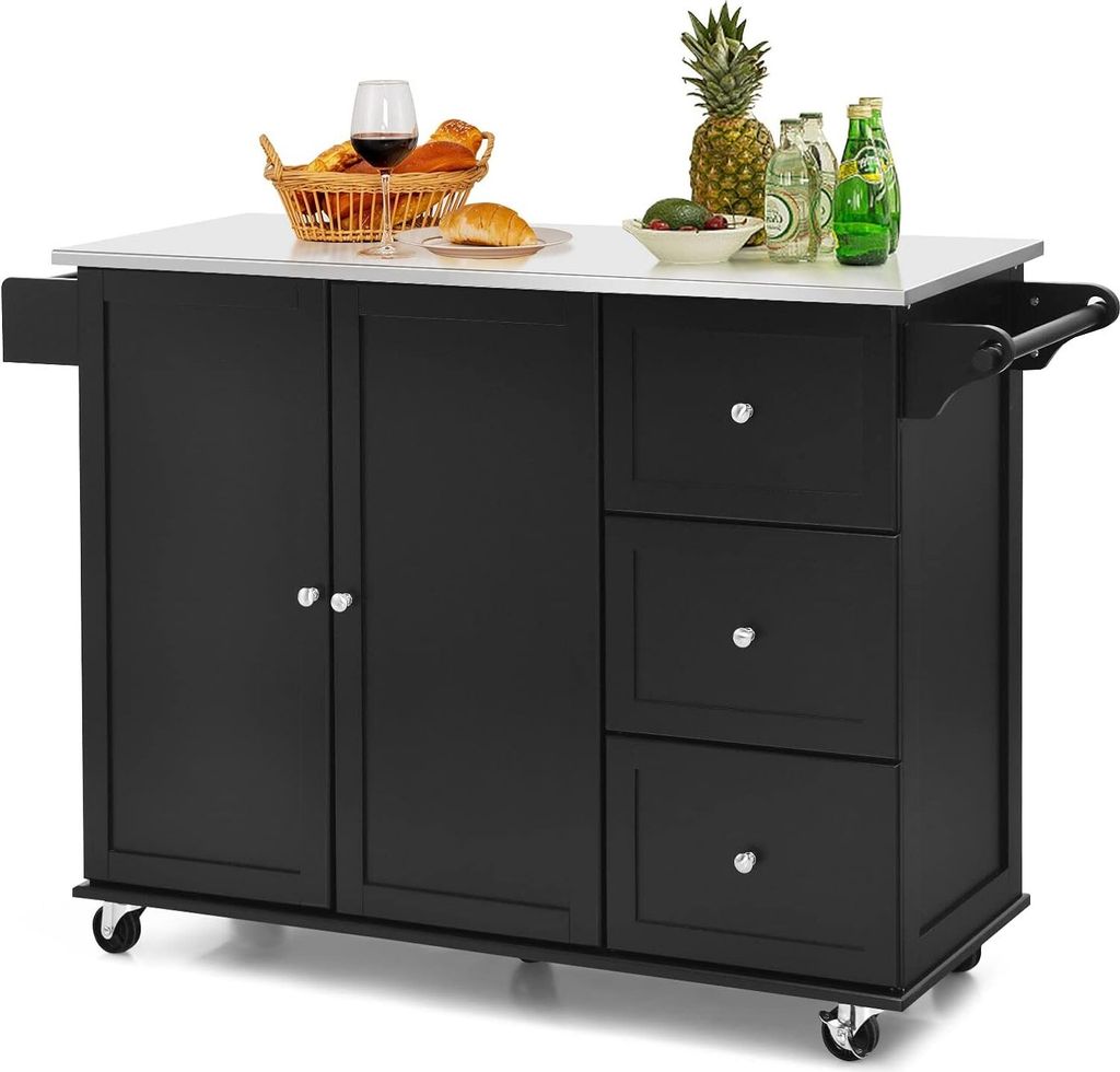 A black kitchen island with a stainless steel countertop is shown against a white background. The island has two doors, three drawers, and a towel rack on the side. It is adorned with a basket of bread, a glass of red wine, a pineapple, avocados, and bottl