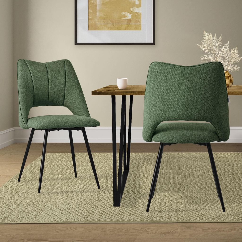 Two green dining chairs are placed around a wooden dining table in a room.