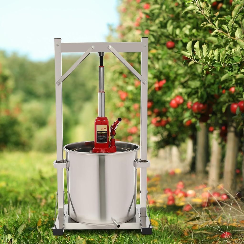 An apple press in an orchard with apple trees in the background.