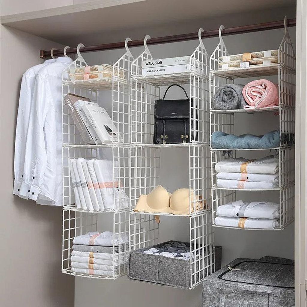 Weißer hängender Kleiderschrank-Organizer aus Kunststoff mit mehreren Gitterablagen, gefüllt mit Kleidung, Büchern und einer Handtasche in einem Kleiderschrank