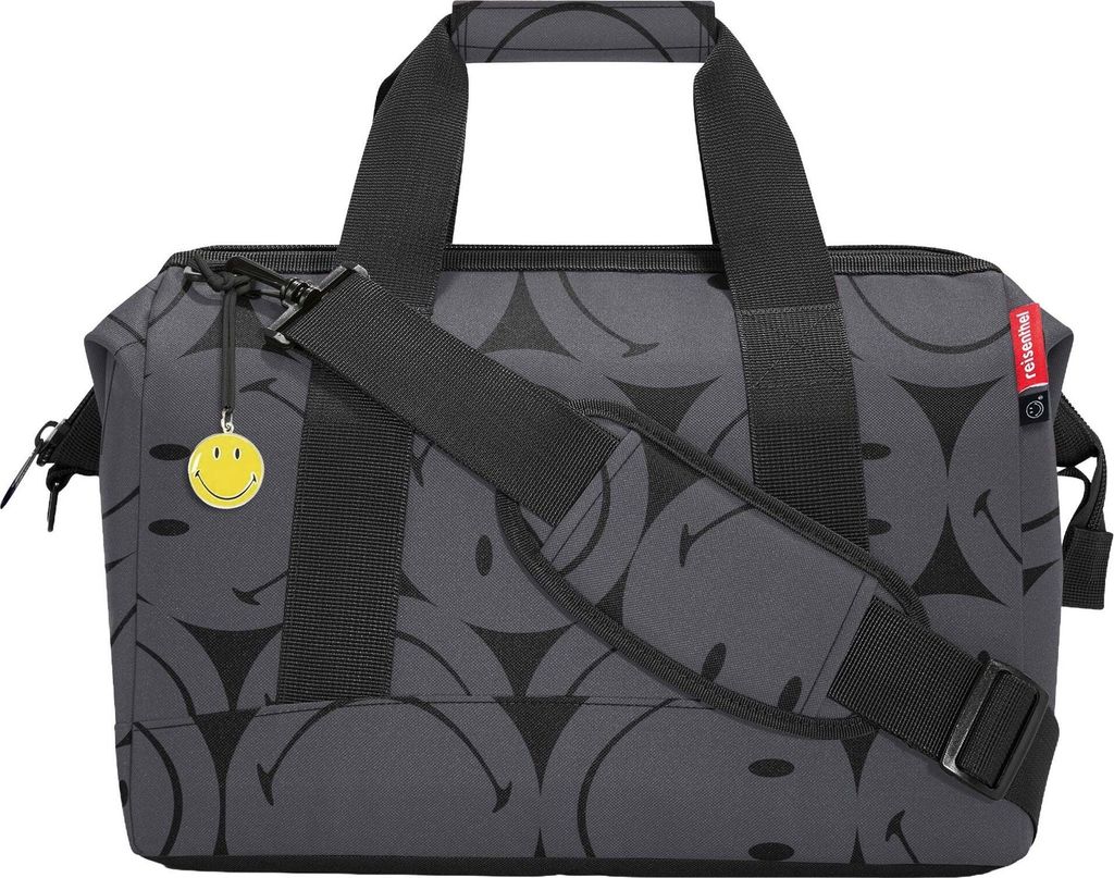 A close-up studio shot of a duffel bag with a smiley face pattern.