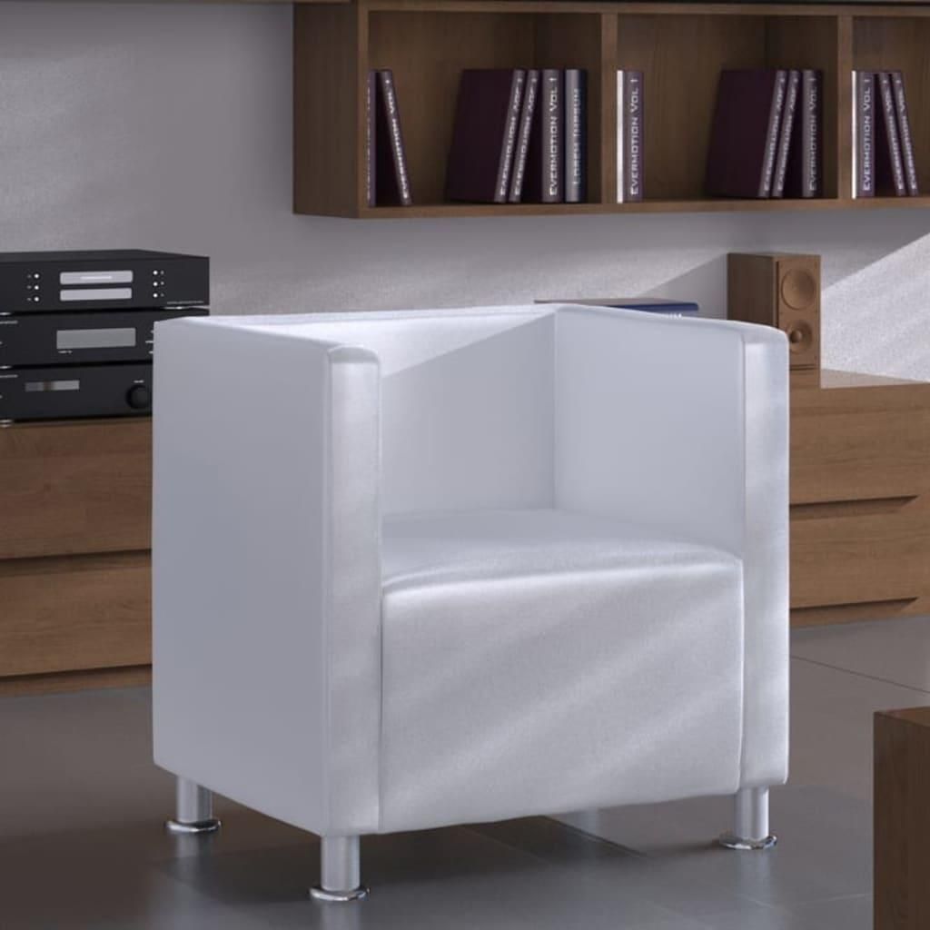 A white cube armchair is shown in a room with wooden furniture and shelves filled with books.
