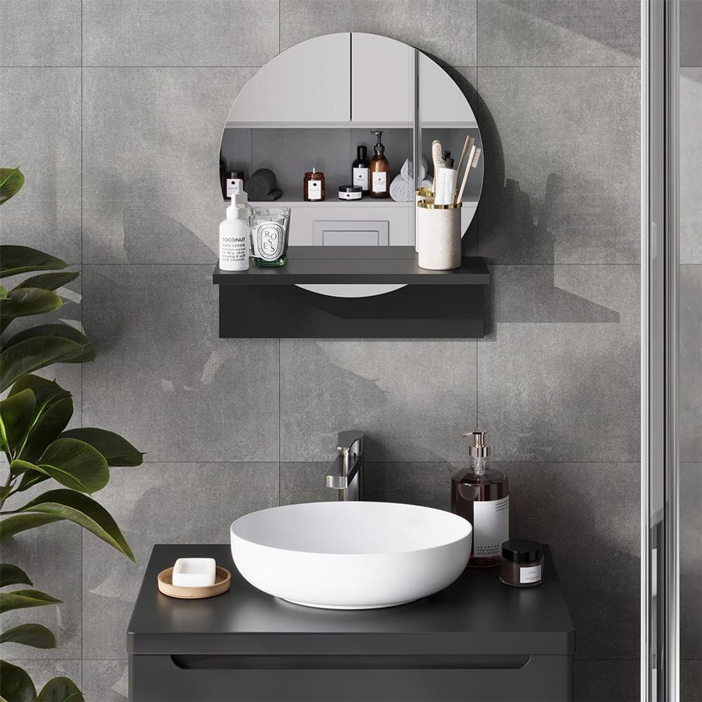 A modern bathroom vanity with a round sink and a circular mirror above it, featuring various toiletries and accessories.