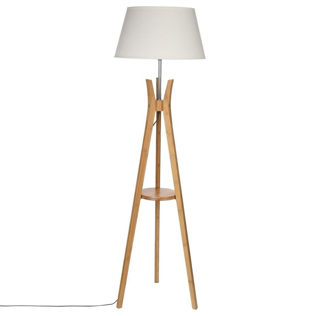 A floor lamp with a white shade and a wooden tripod base with a small shelf.