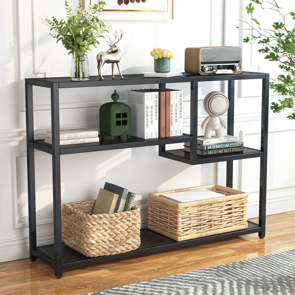 A black metal console table with shelves, decorated with various items like books, baskets, and decorative objects.