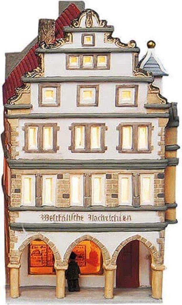 A ceramic miniature house with illuminated windows, depicting a traditional building with arched storefronts.