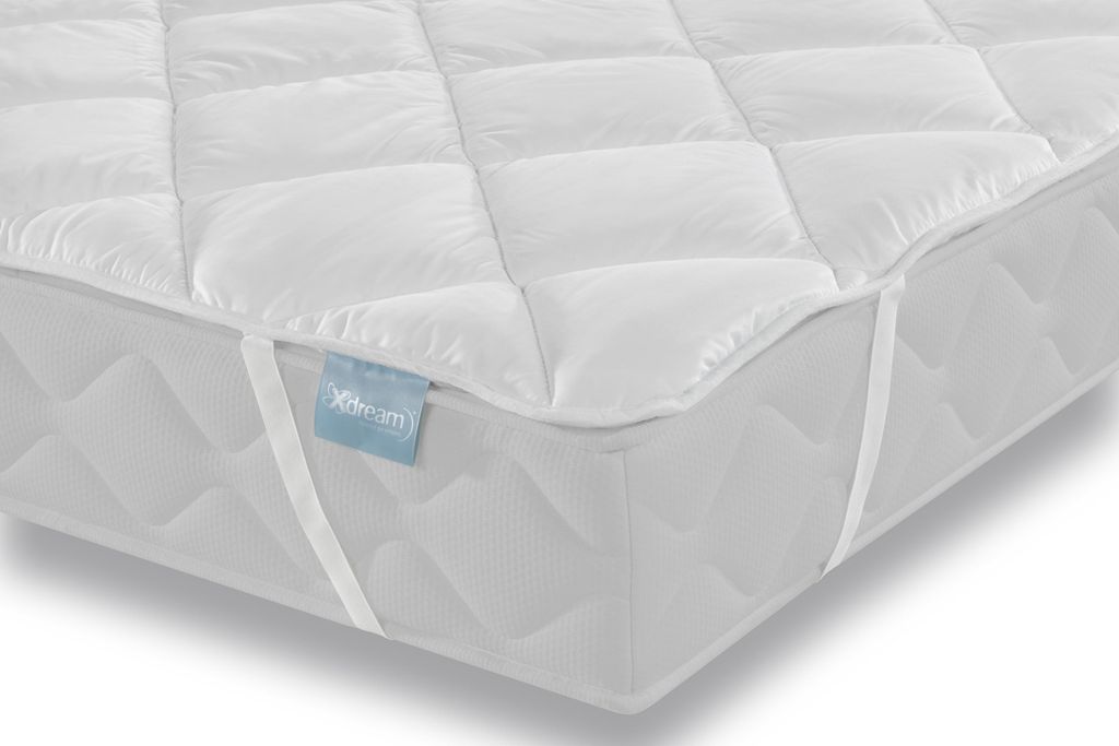 A close-up view of a white quilted mattress topper placed on a mattress.