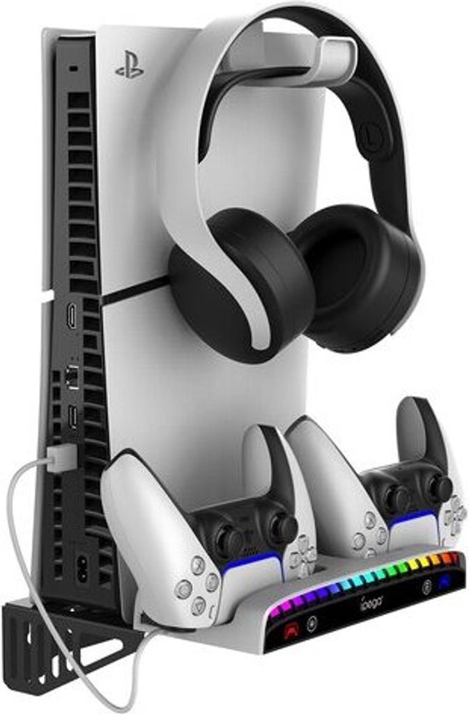 A white charging stand for a PlayStation 5 console, holding two controllers and a pair of headphones.