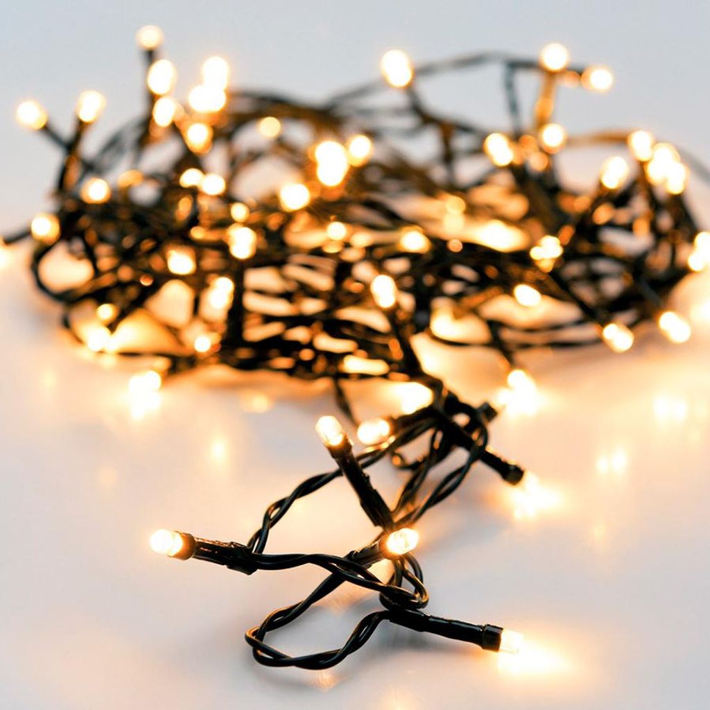A close-up of a string of warm white LED lights on a white surface.